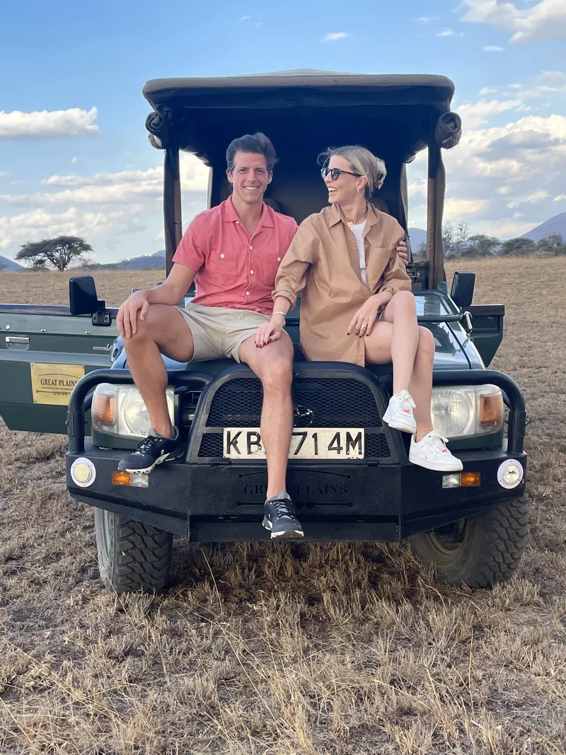 Jason and his wife sitting on the front of a safari vehicle in Kenya